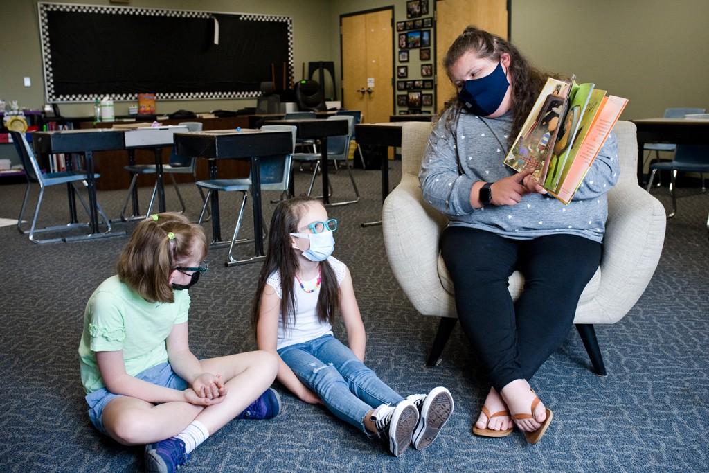 A U N E students reads to two elementary school special education students