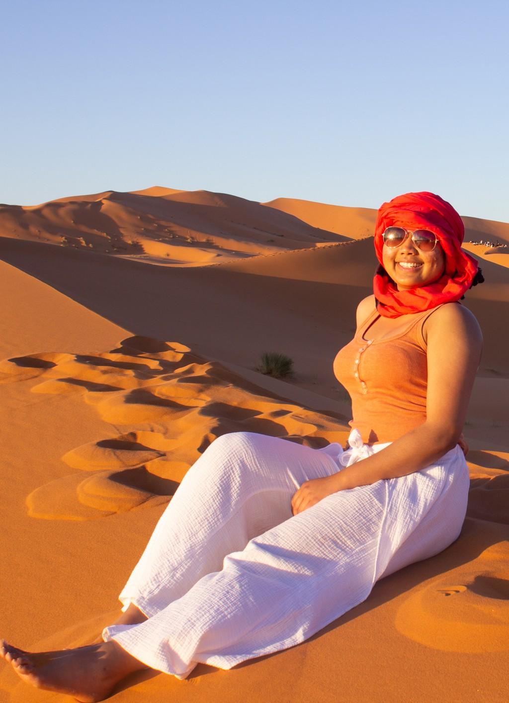 A student sitting on the sand of a Moroccan desert